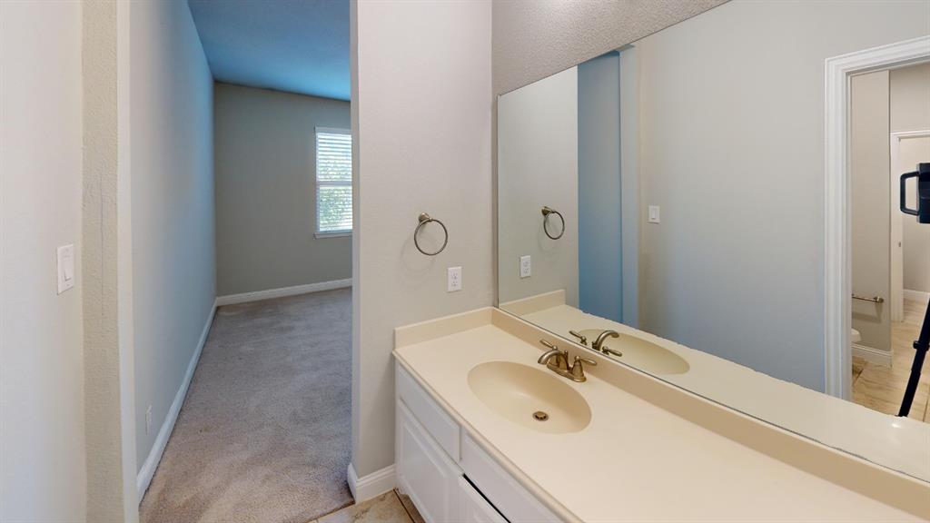 Vanity featuring a solid-surface integrated sink, white cabinetry, metallic faucet hardware, and a large wall-mounted mirror