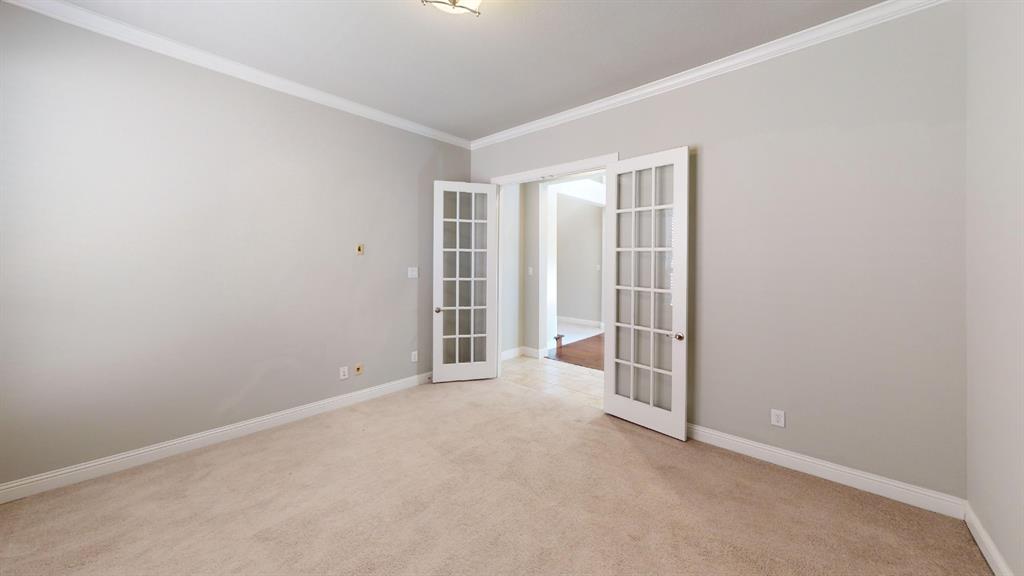 Room featuring neutral wall paint, crown molding, plush wall-to-wall carpeting, and white glass-paned French doors