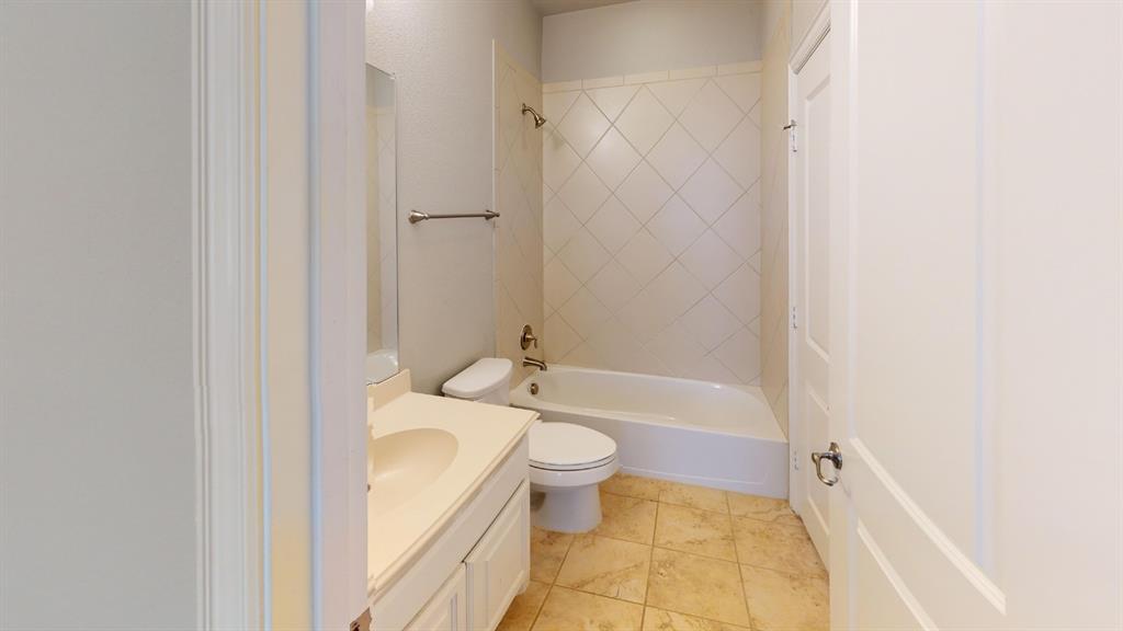 Bathroom featuring a vanity with integrated sink, tile flooring, and a tub with diamond-pattern tile surround