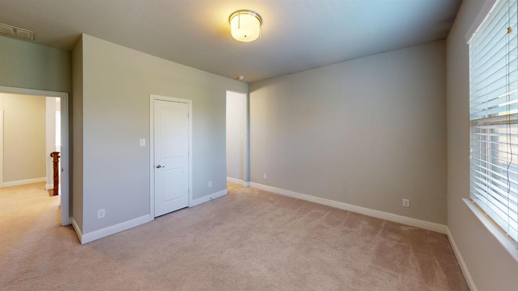 Neutral-toned interior space featuring wall-to-wall carpeting, a multi-panel door, and a flush-mount drum light fixture