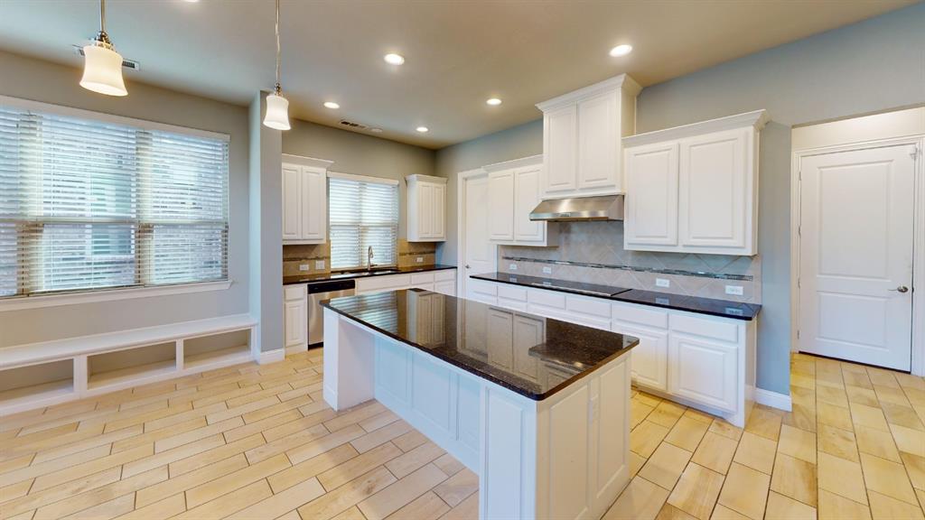 Kitchen featuring an island with stone countertops, white cabinetry, tile backsplash, wood-finish flooring, and recessed lighting Kitchen featuring an island with stone countertops, white cabinetry, tile backsplash, wood-finish flooring, and recessed lighting