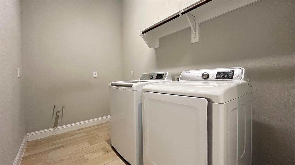 Utility space featuring wood-finish flooring, neutral wall tones, and a built-in overhead shelf with a garment rod