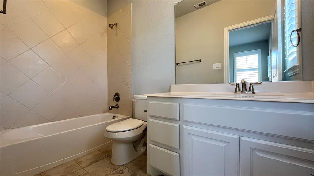 Bathroom featuring a white vanity cabinet with a solid surface countertop, diagonal-set wall tile surrounding the bathtub, tile flooring, and a large wall-mounted mirror