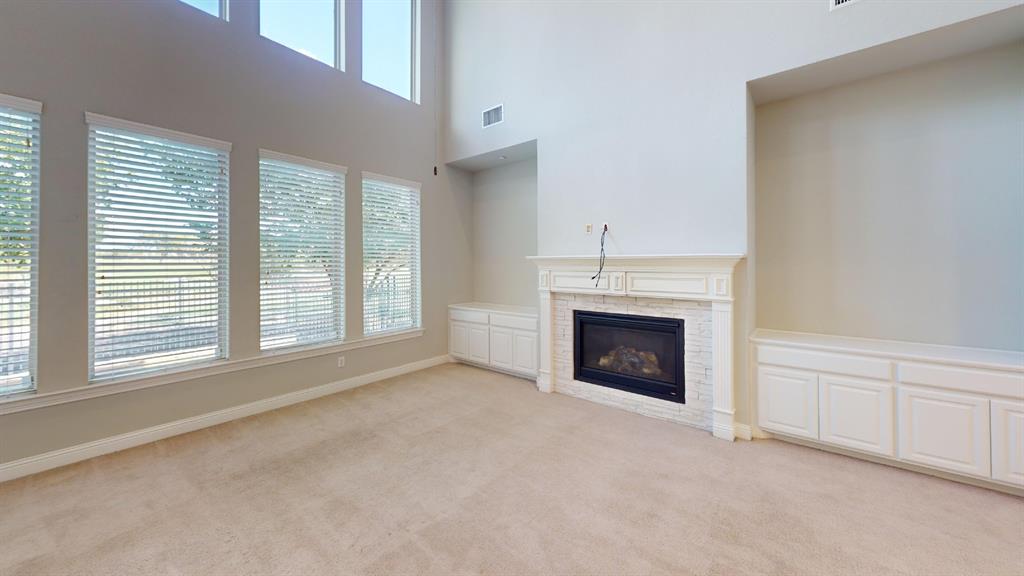 High ceilings with tiered windows, fireplace with a painted brick surround, and white built-in cabinetry High ceilings with tiered windows, fireplace with a painted brick surround, and white built-in cabinetry