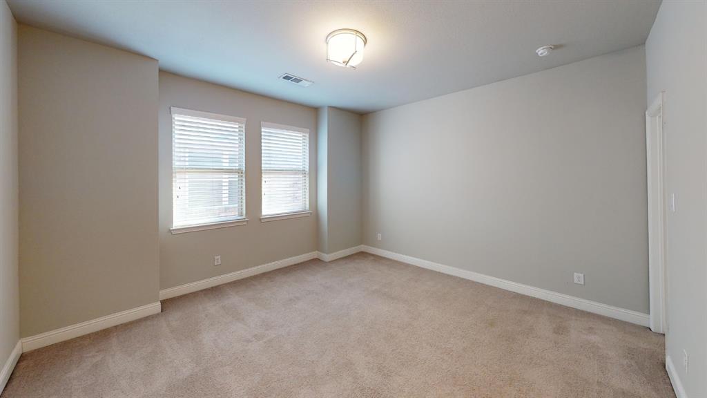 Neutral-toned interior space featuring neutral wall paint, wall-to-wall carpeting, dual windows with horizontal blinds, and a central ceiling-mounted light fixture