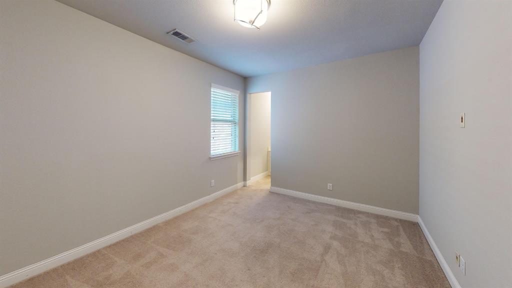 Neutral wall tones, wall-to-wall carpeting, single-pane window with horizontal blinds, and a central overhead flush-mount light fixture