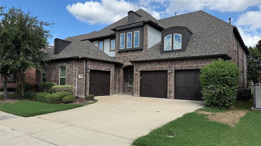 Multi-level exterior featuring a brick facade, multi-gabled roofline, three-car garage with carriage-style doors, and decorative arched window dormers Multi-level exterior featuring a brick facade, multi-gabled roofline, three-car garage with carriage-style doors, and decorative arched window dormers