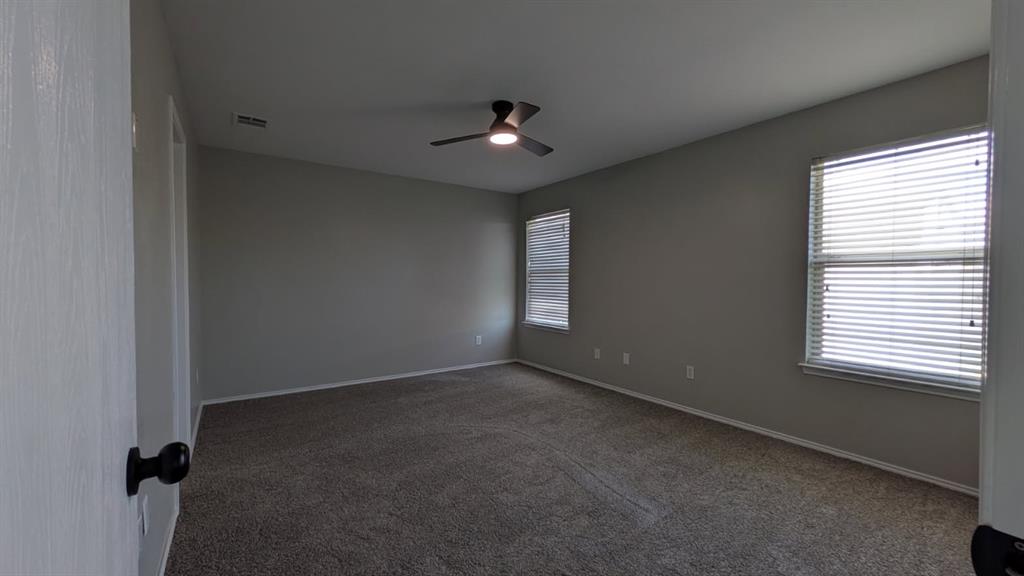 Neutral-toned walls, wall-to-wall carpeting, dual windows with horizontal blinds, and a central ceiling fan with integrated lighting