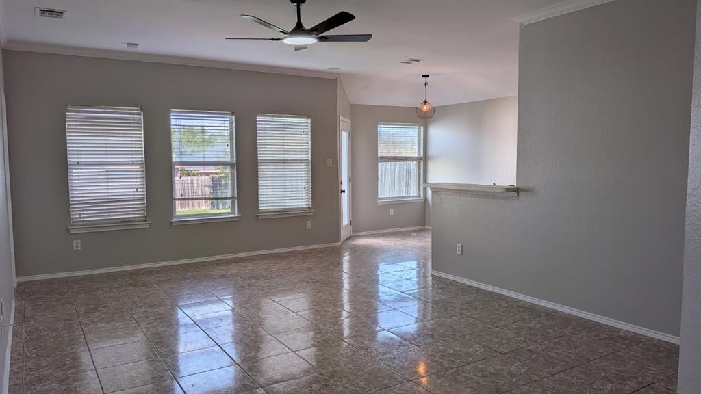 Living area featuring tile flooring, neutral wall paint, three large windows with horizontal blinds, a ceiling fan with integrated lighting, and a partial height wall divider Living area featuring tile flooring, neutral wall paint, three large windows with horizontal blinds, a ceiling fan with integrated lighting, and a partial height wall divider