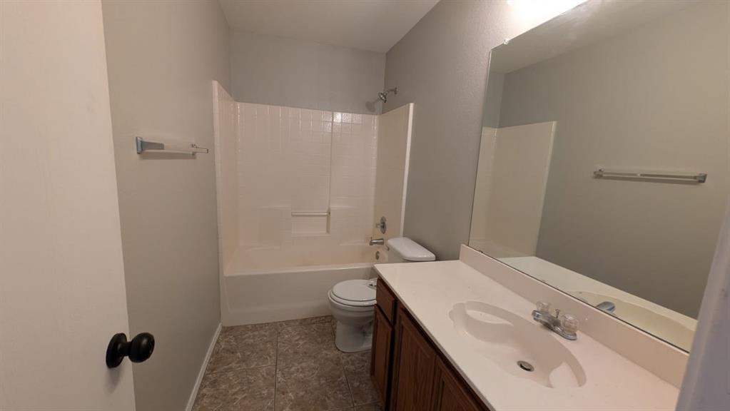 Bathroom featuring a vanity with a white countertop and integrated sink, full-width mirror, tile flooring, and a tub-shower combination with tiled surround