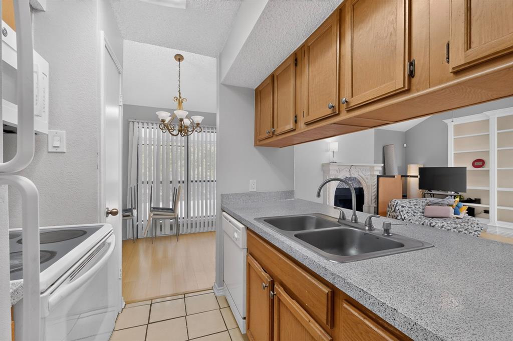 Kitchen featuring light wood cabinetry, dual-basin stainless steel sink, and light speckled countertops