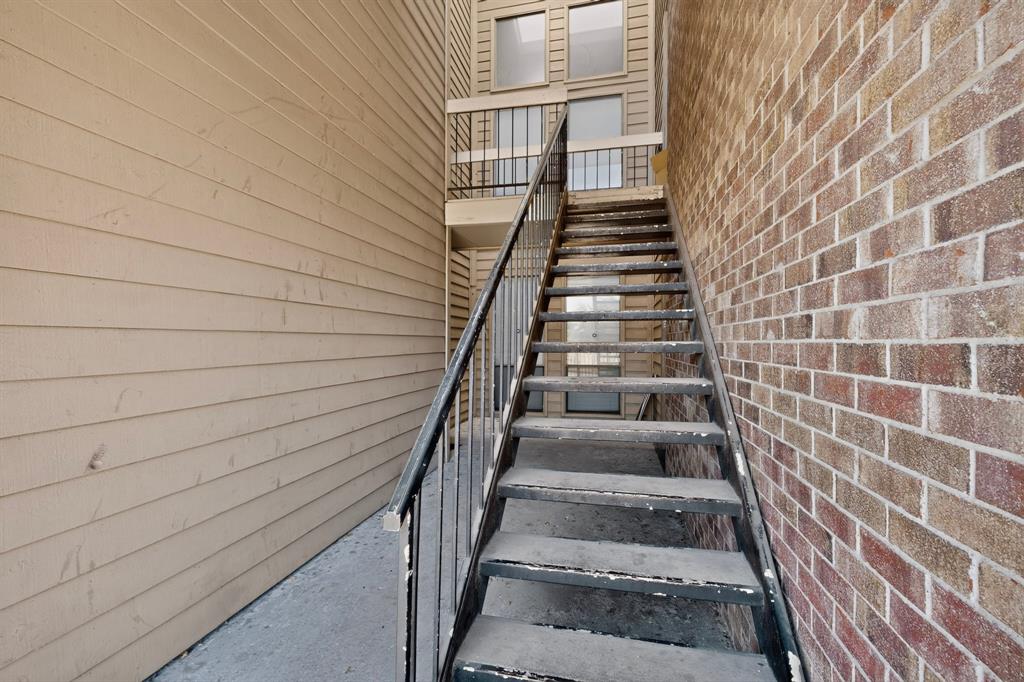 Exterior staircase with metal railings, brick facade, and horizontal siding