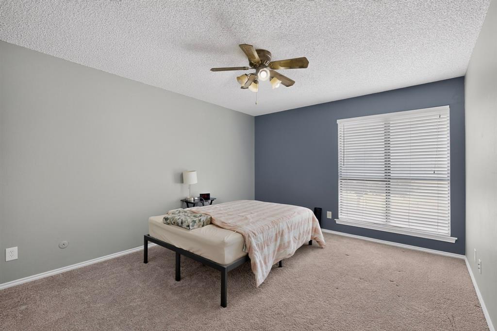 Spacious room featuring carpeting, a prominent window with blinds, and a ceiling fan with integrated lighting