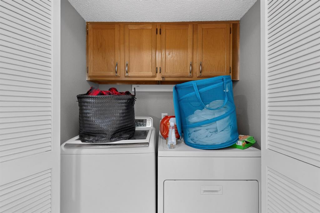 Laundry area with wood-finish cabinetry and louvered bifold doors