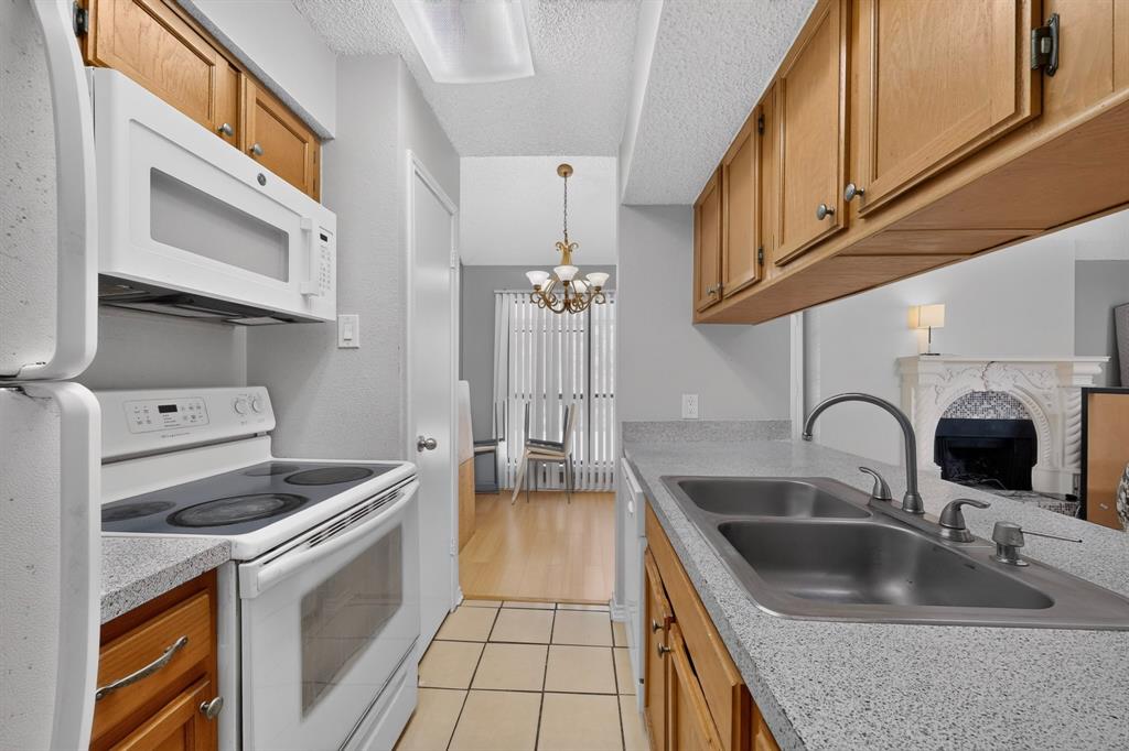 Kitchen with wood cabinetry, light-toned countertops, and a double basin sink