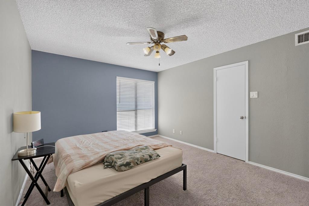 Carpeted room with a ceiling fan, window with horizontal blinds, and a white door