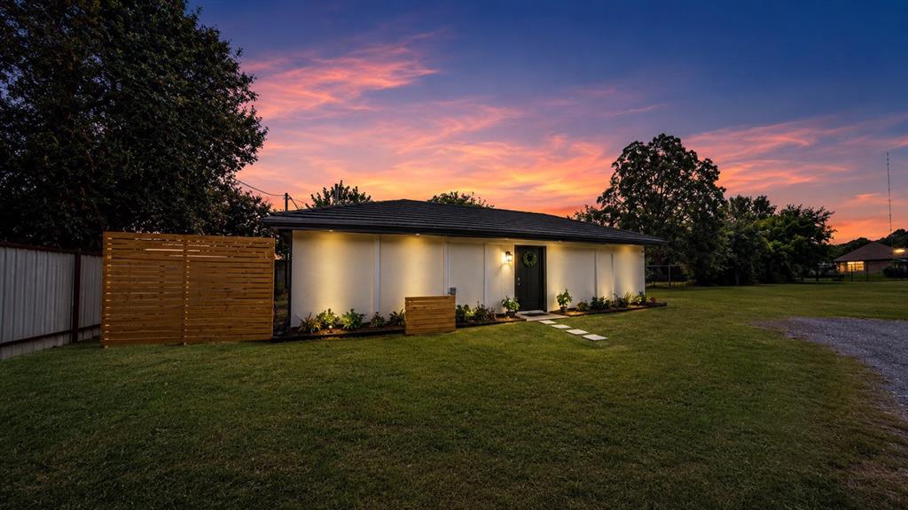 Single-story exterior featuring white siding, a hip roof, horizontal wood privacy fencing, and stone paver walkway Single-story exterior featuring white siding, a hip roof, horizontal wood privacy fencing, and stone paver walkway
