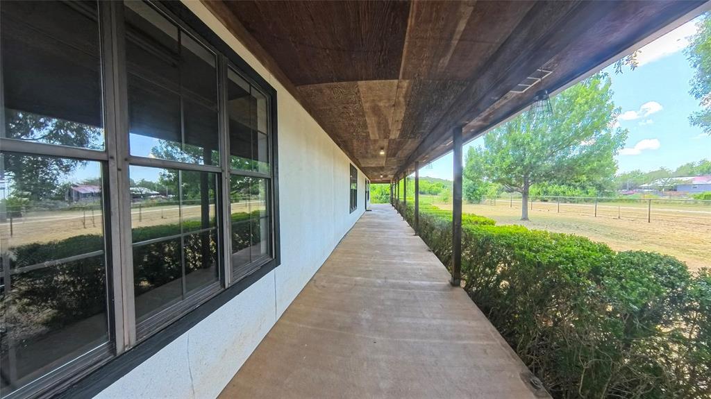 Covered exterior porch featuring wood-plank ceiling, concrete flooring, and grid-pattern window panes Covered exterior porch featuring wood-plank ceiling, concrete flooring, and grid-pattern window panes