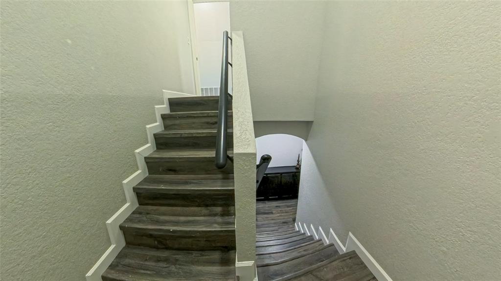 Staircase featuring wood-finish treads and a dark metal handrail