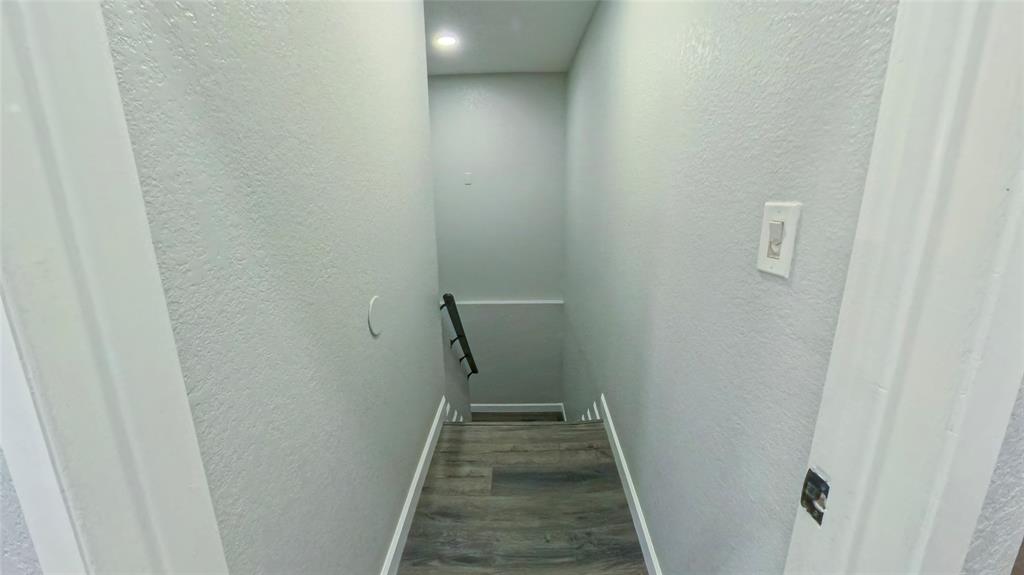 Staircase featuring wood-finish flooring, neutral wall paint, recessed lighting, and a metal handrail