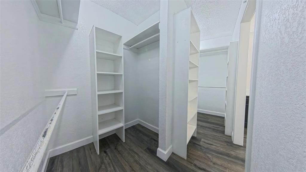 Walk-in closet featuring wood-finish flooring, built-in shelving towers, and multiple hanging rods