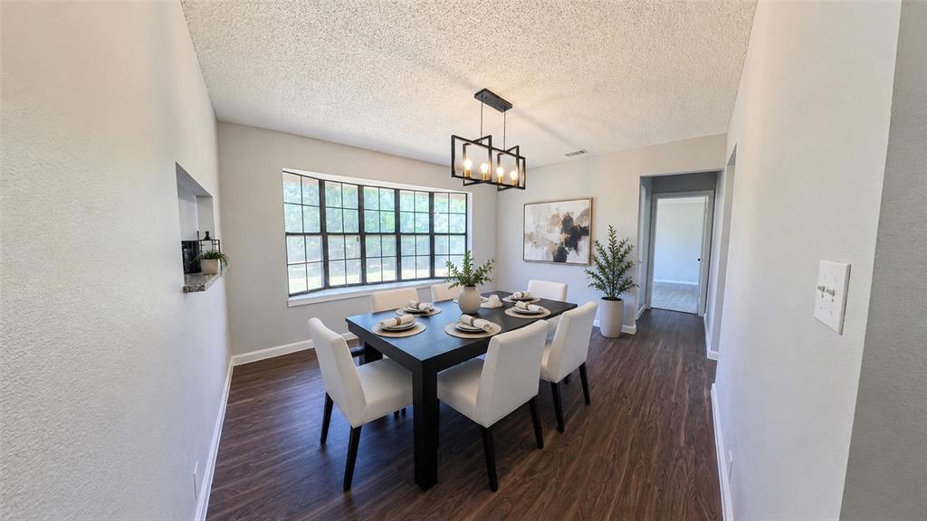 Dining area featuring wood-finish flooring, a multi-pane bay window, and a linear black metal chandelier