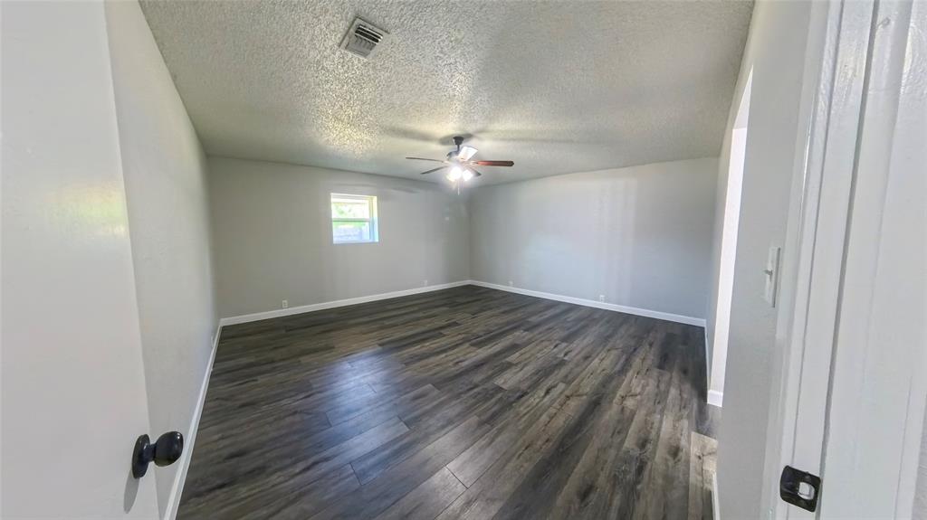 Interior space featuring wood-finish flooring, neutral wall paint, and a ceiling-mounted light fixture with a fan
