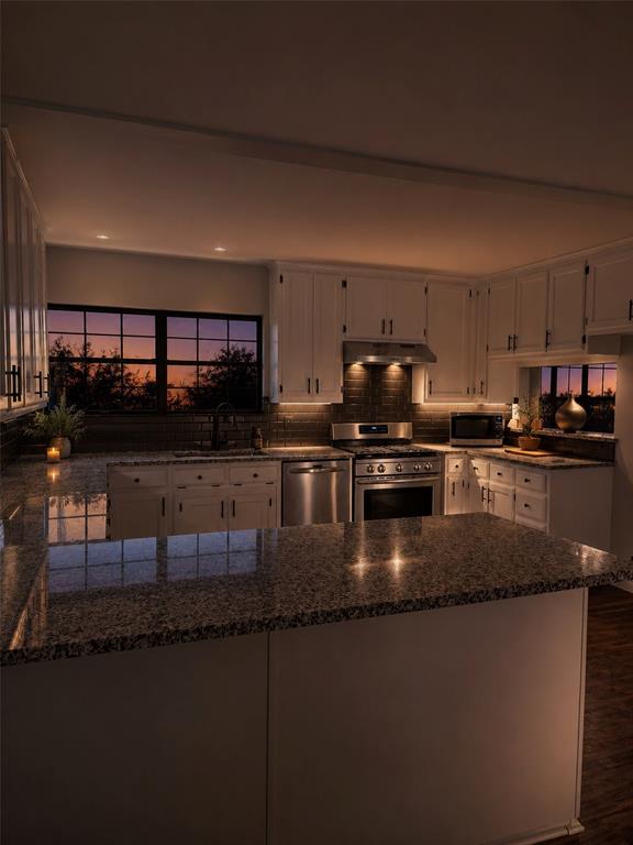 Kitchen featuring white cabinetry, stone countertops, dark-toned tile backsplash, and stainless steel appliances