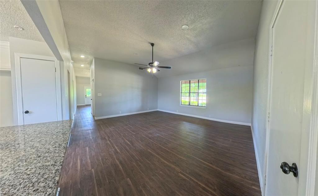 Vaulted ceilings featuring a central light-integrated ceiling fan, wood-finish flooring, and a multi-pane window
