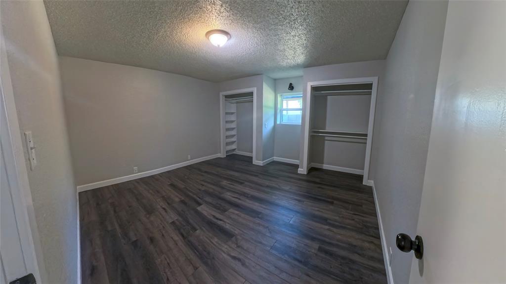 Room featuring wood-finish flooring, dual closets with built-in shelving, and a natural light-admitting window