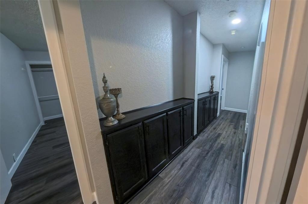 Built-in dark-toned cabinetry with solid-surface countertops, wood-finish flooring, and recessed ceiling lighting