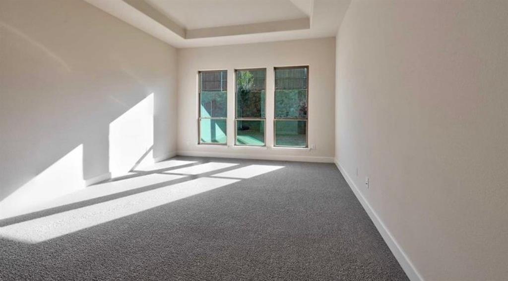 Tray ceiling, neutral wall tones, and three large windows featuring grid patterns and exterior exposure