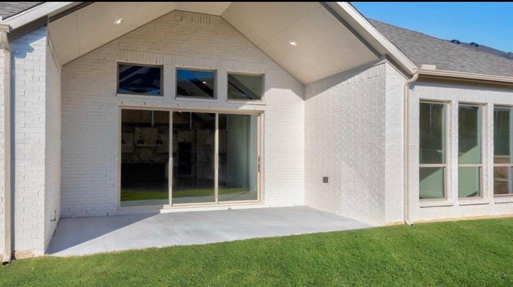 Covered patio with painted brick exterior, vaulted ceiling, recessed lighting, and expansive glass sliding doors topped with triple transom windows