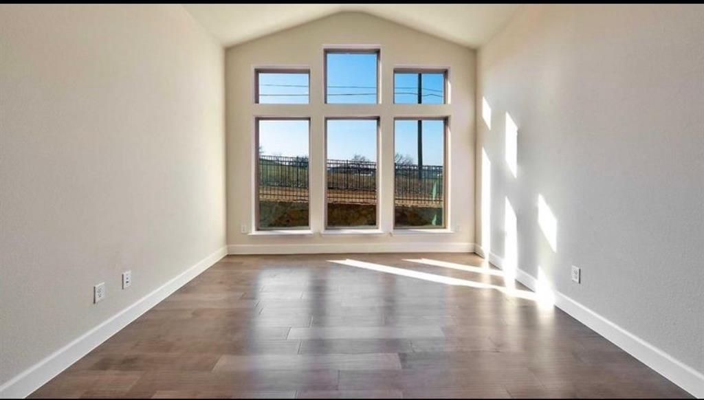 Vaulted ceiling featuring expansive floor-to-ceiling windows and wood-finish flooring