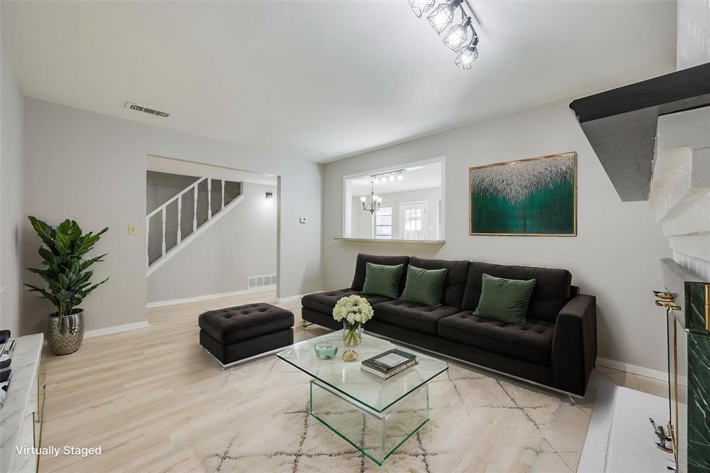 Living area featuring wood-finish flooring, a painted brick fireplace with a decorative mantel, and a pass-through window with a ledge
