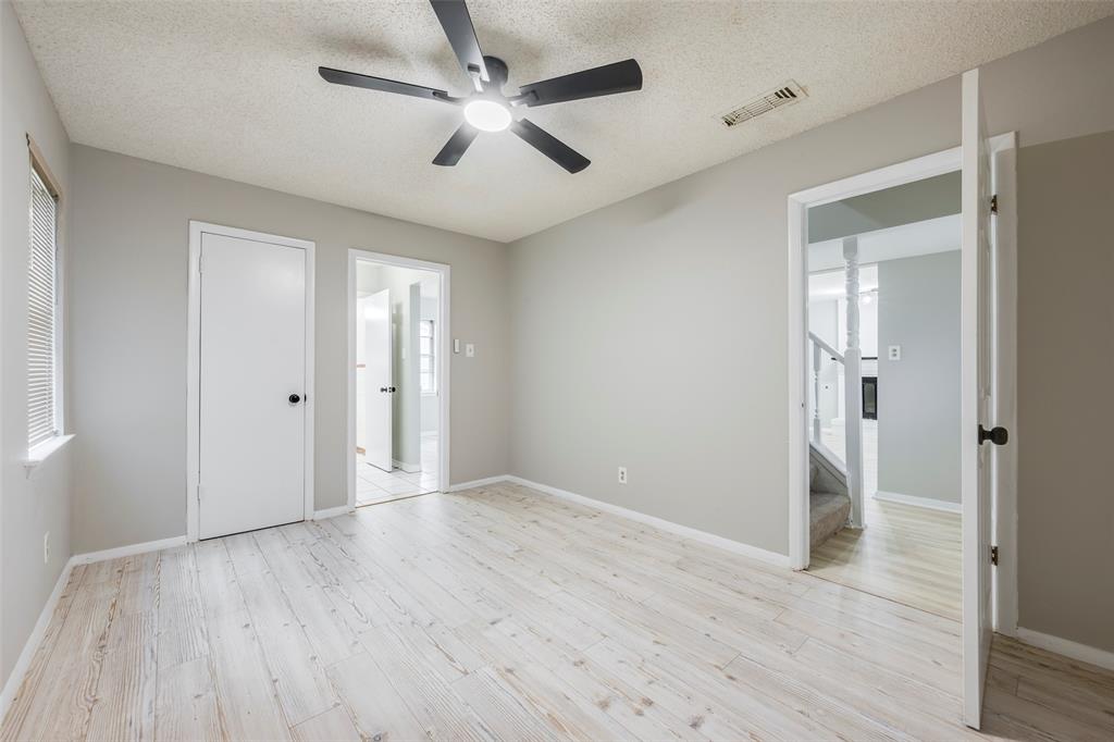 Room featuring wood-finish flooring, a matte black ceiling fan with integrated lighting, neutral wall paint, and multiple interior doors