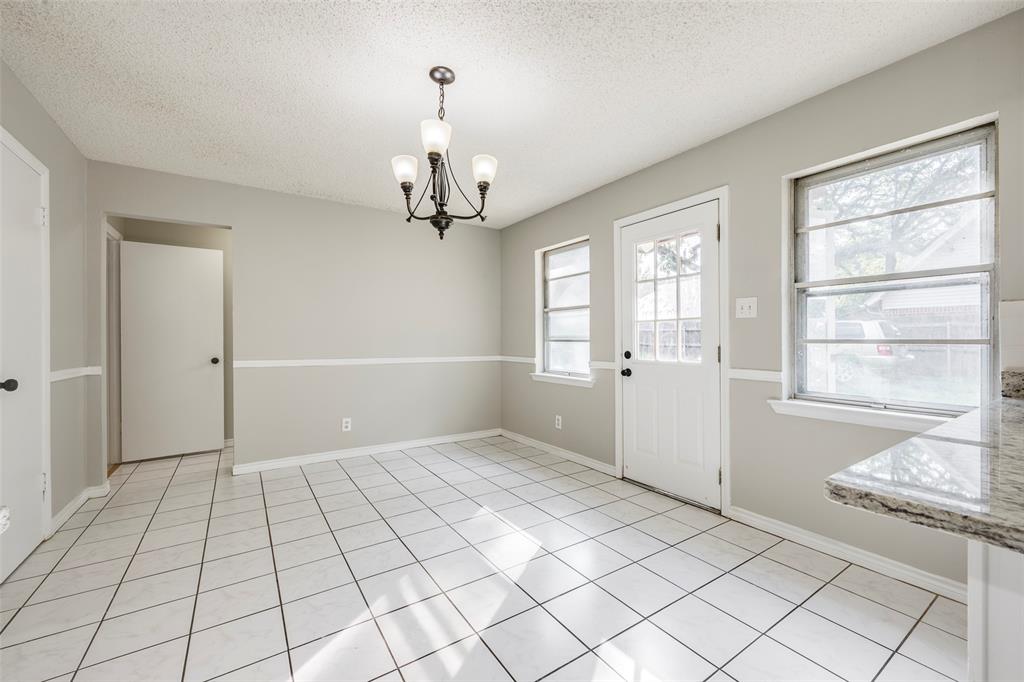 Neutral-toned room featuring tile flooring, chair rail molding, a multi-light chandelier, and a exterior door with a glass pane