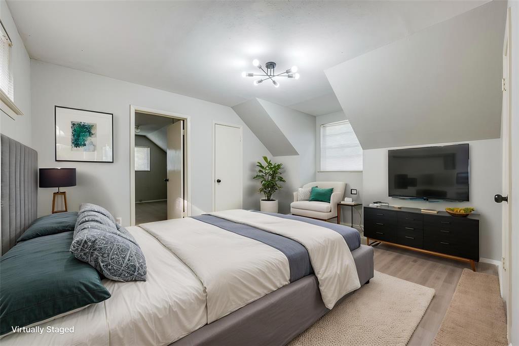 Room featuring sloped ceilings, wood-finish flooring, and a multi-arm modern light fixture