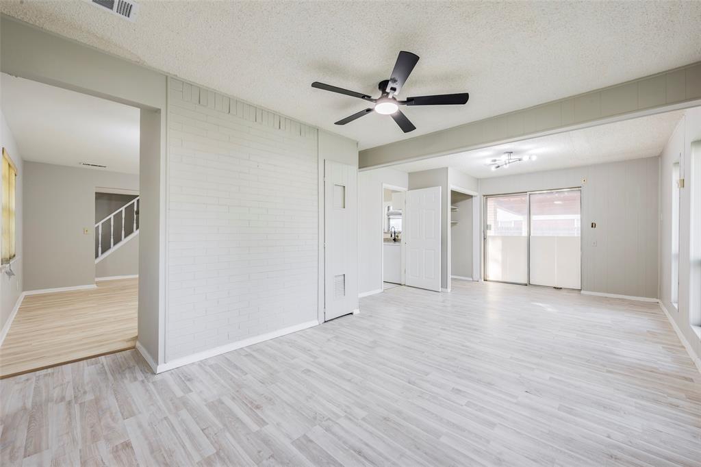 Interior space featuring wood-finish flooring, a painted brick partition wall, a ceiling fan with integrated lighting, and sliding glass doors