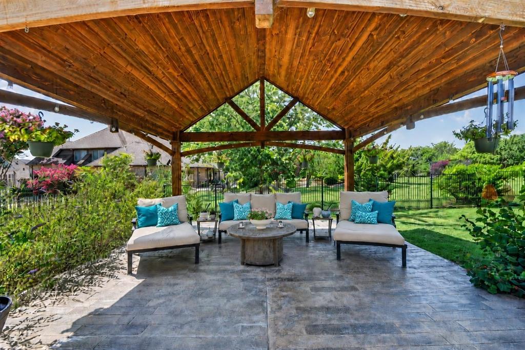 Covered outdoor patio featuring a vaulted tongue-and-groove wood ceiling, exposed timber framing, and stamped concrete flooring