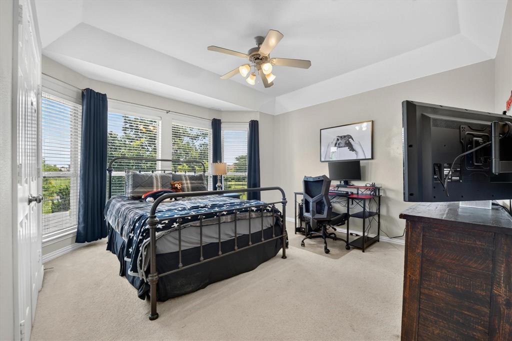 Tray ceiling featuring a central light fixture with an integrated ceiling fan, neutral carpeting, and multi-paneled windows