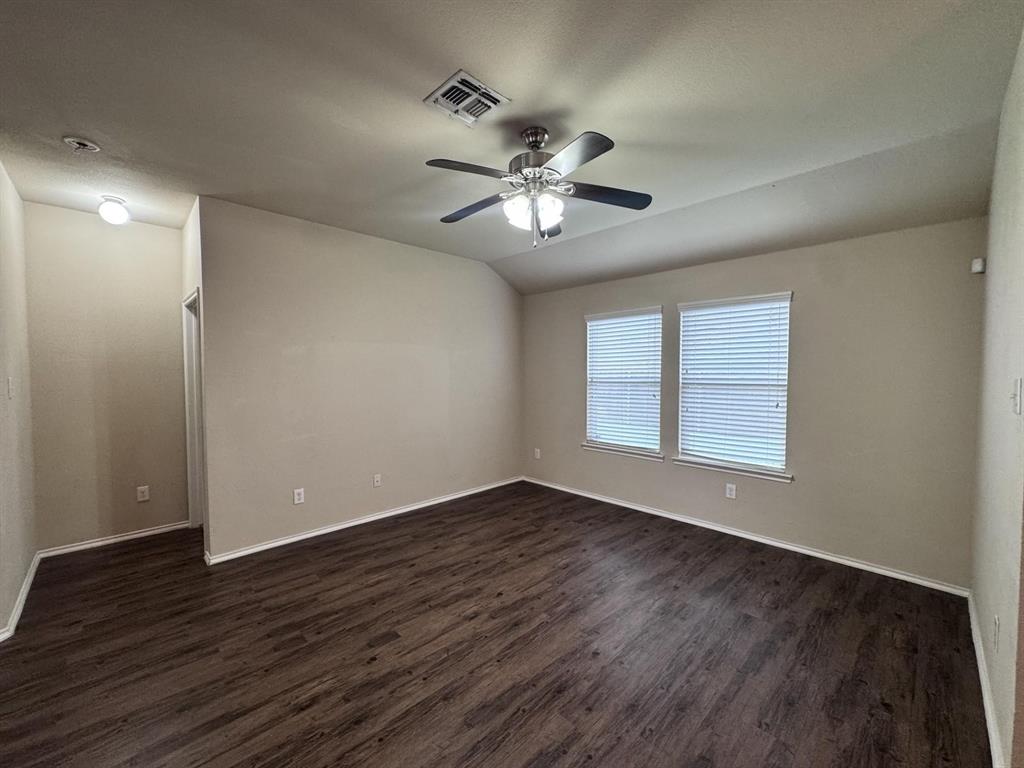 Room featuring wood-finish flooring, vaulted ceilings, dual windows with horizontal blinds, and a multi-light ceiling fan