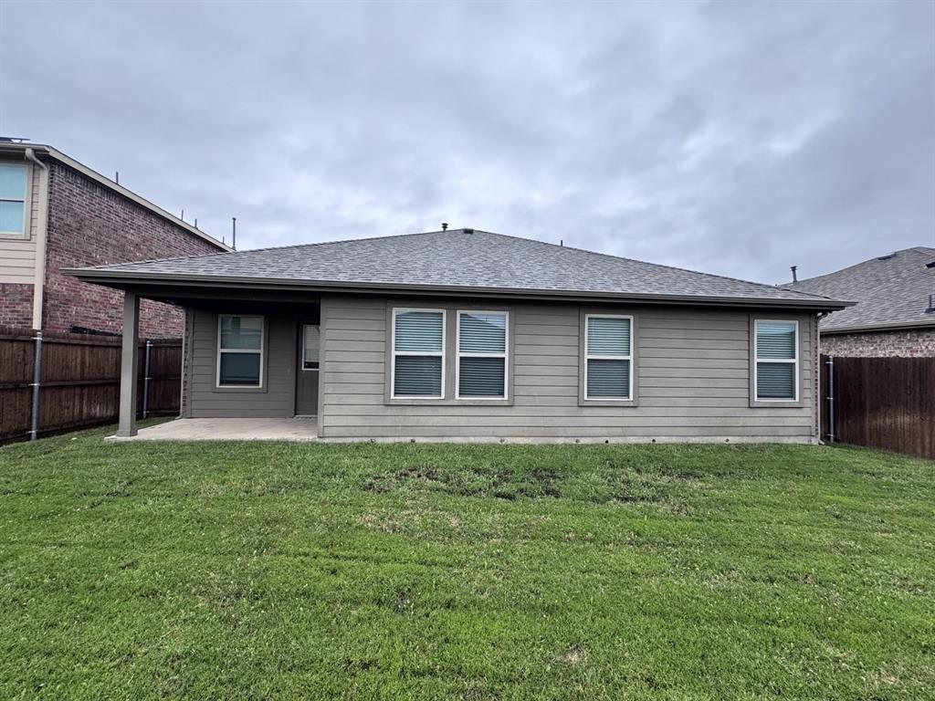 Rear exterior featuring a concrete covered patio, horizontal lap siding, asphalt shingle roof, and a fenced backyard