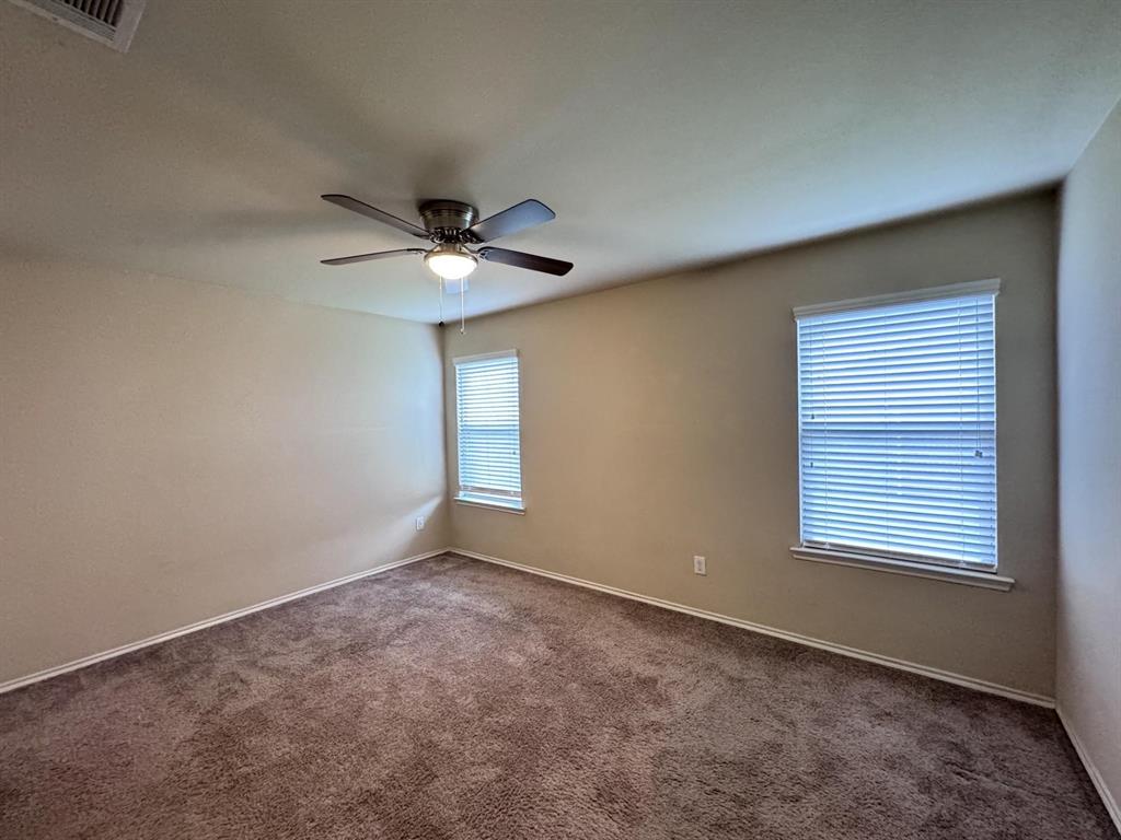 Neutral-toned walls, wall-to-wall carpeting, ceiling fan with integrated lighting, and windows featuring horizontal blinds