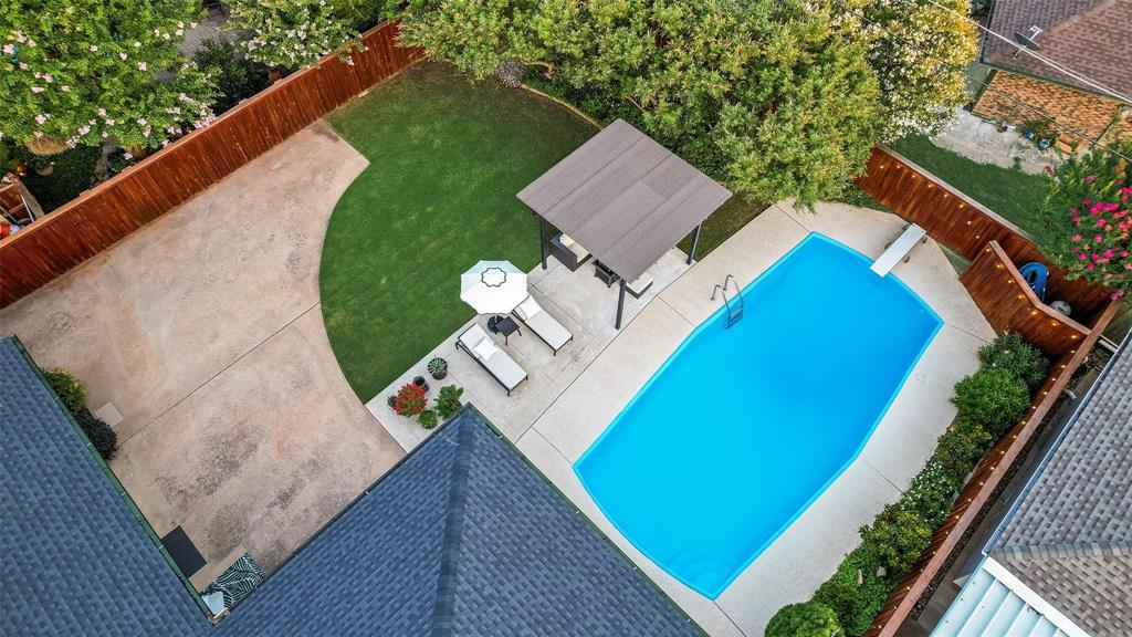 Backyard featuring a concrete pool with a diving board, covered pergola, expansive concrete patio, and fenced perimeter
