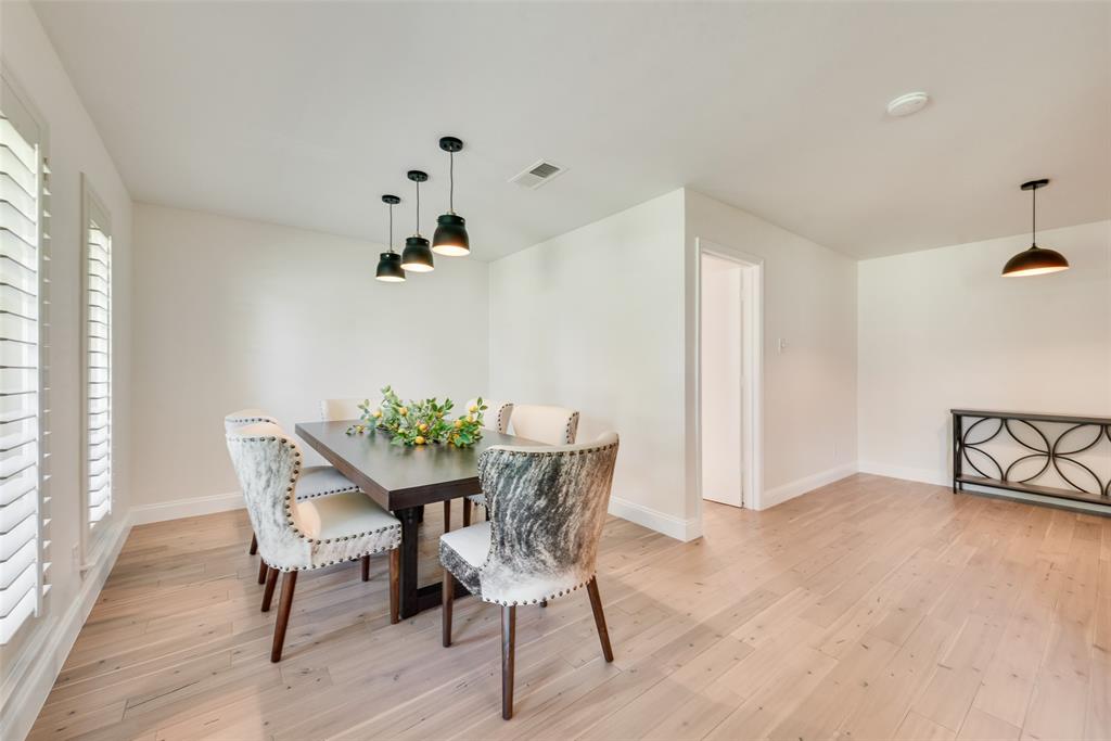Dining area featuring wood-finish flooring, plantation shutters, and multi-tier pendant lighting Dining area featuring wood-finish flooring, plantation shutters, and multi-tier pendant lighting