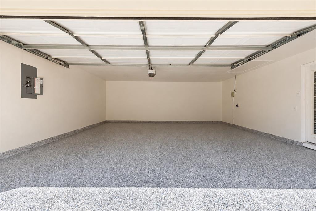 Attached two-car garage featuring speckled epoxy flooring, white painted walls, and an overhead automatic door opener