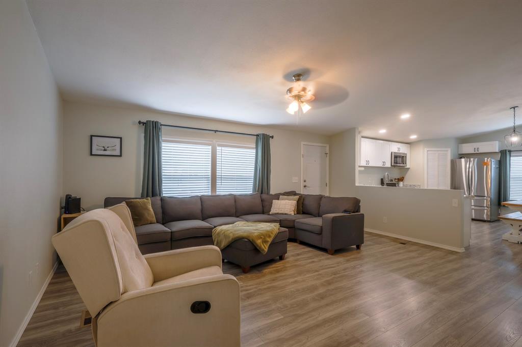 Living area featuring wood-finish flooring, recessed lighting, and a ceiling fan, including a kitchen with white cabinetry and stainless steel appliances