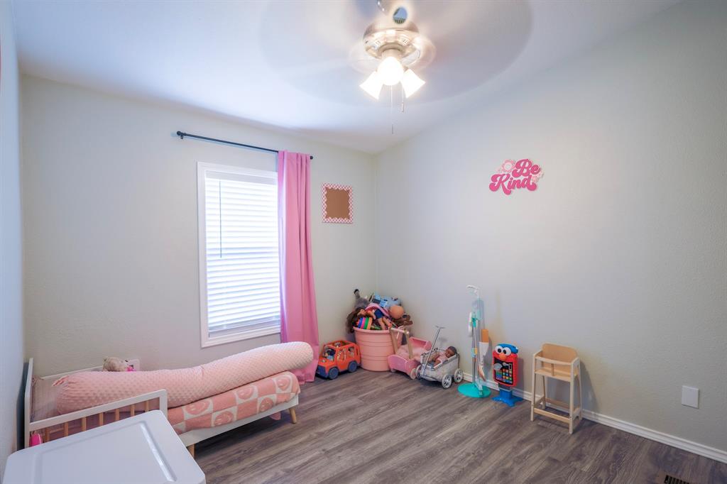 Bedroom featuring wood-finish flooring, a neutral wall palette, a multi-light ceiling fan, and a window with a mounted curtain rod