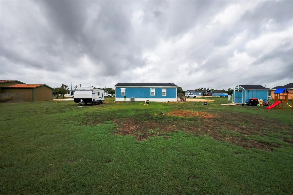 Expansive lot featuring a detached storage shed and a blue-sided structure with a dark shingle roof